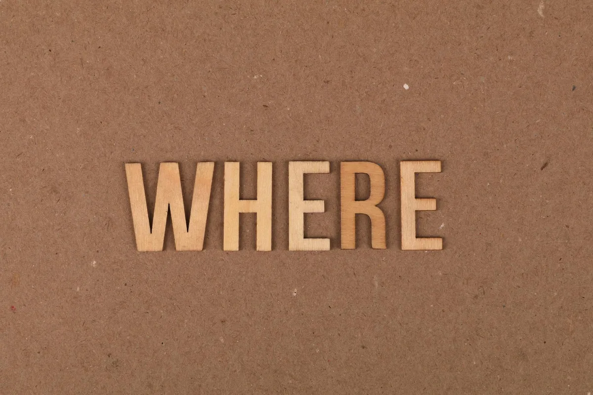 Wooden letters spelling "WHERE" on a brown cardboard background