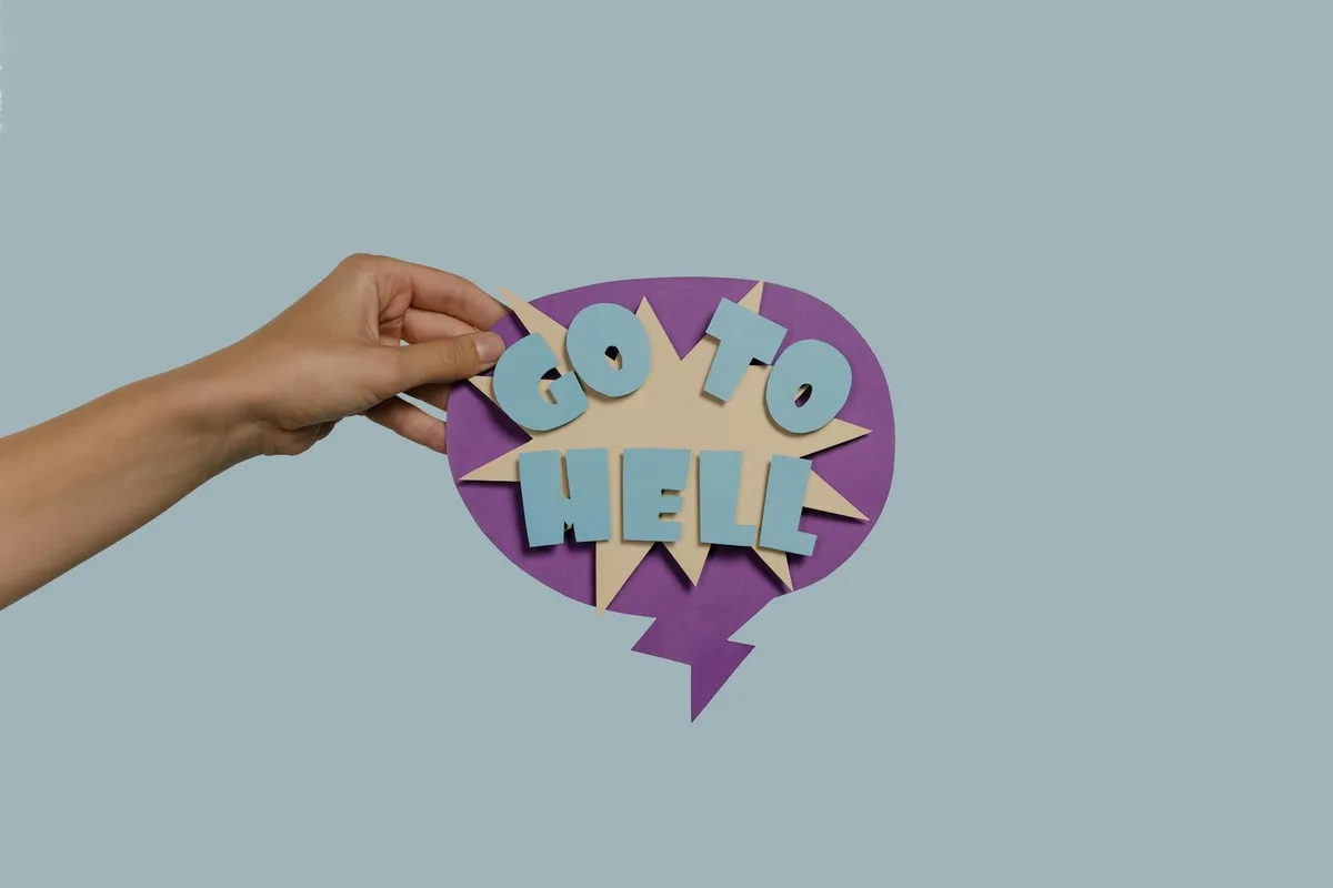 Hand holding a purple speech bubble craft with "DO IT WELL" text and wide eyes against a blue background