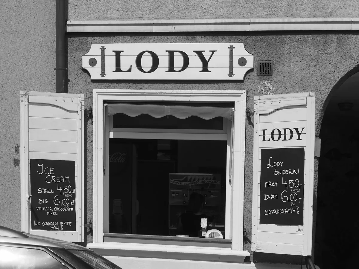 Black and white photo of Lody ice cream shop storefront with white trim and menu boards on the doors.