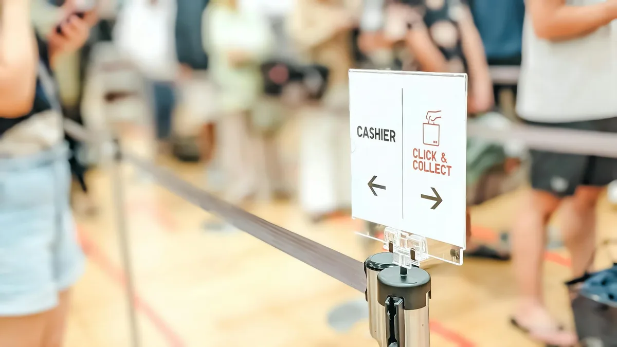 Directional sign at a retail queue showing "CASHIER" and "CLICK & COLLECT" options with arrows pointing left and right.