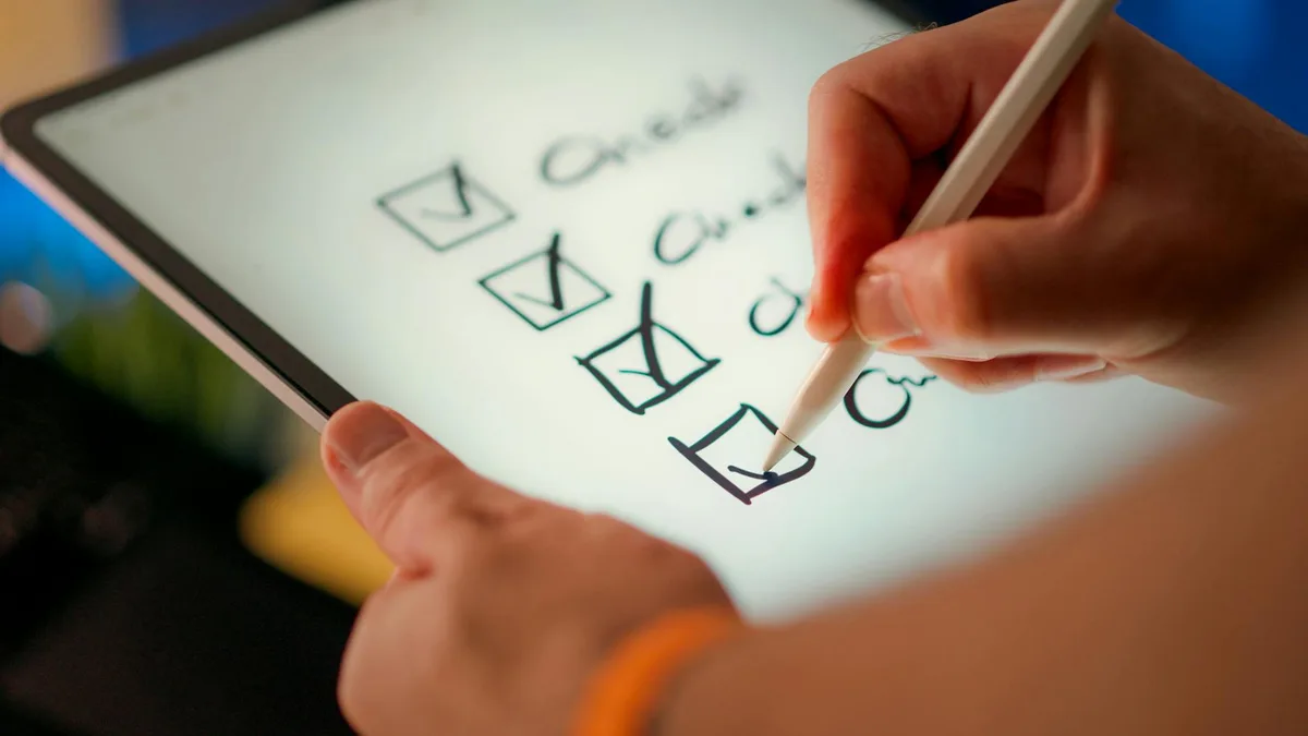 Person using stylus to check boxes on a digital checklist on tablet screen