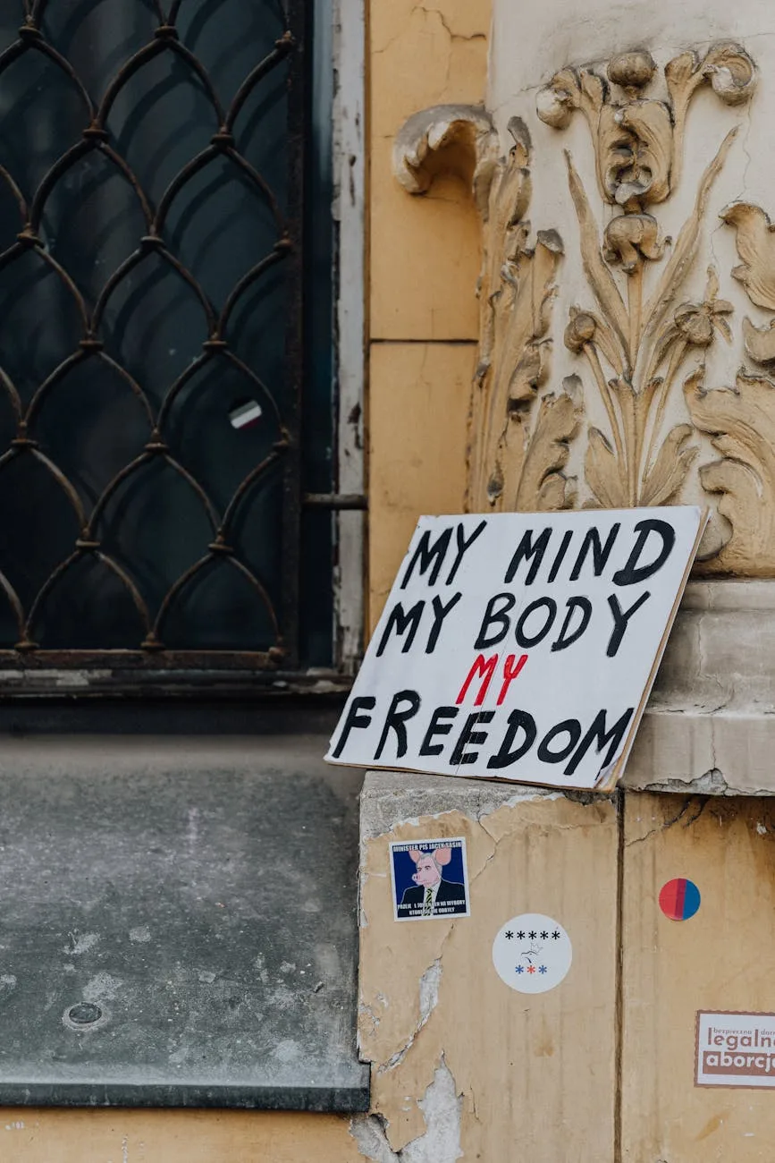 A protest sign reading "MY MIND MY BODY MY FREEDOM" leaned against a historic building entrance with ornate architectural details.
