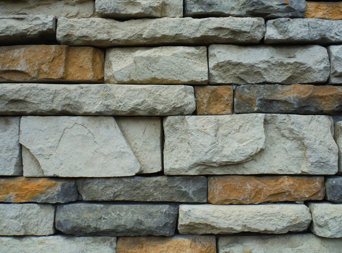 Close-up of stacked stone wall showing natural texture, varied earth tones, and rustic masonry construction